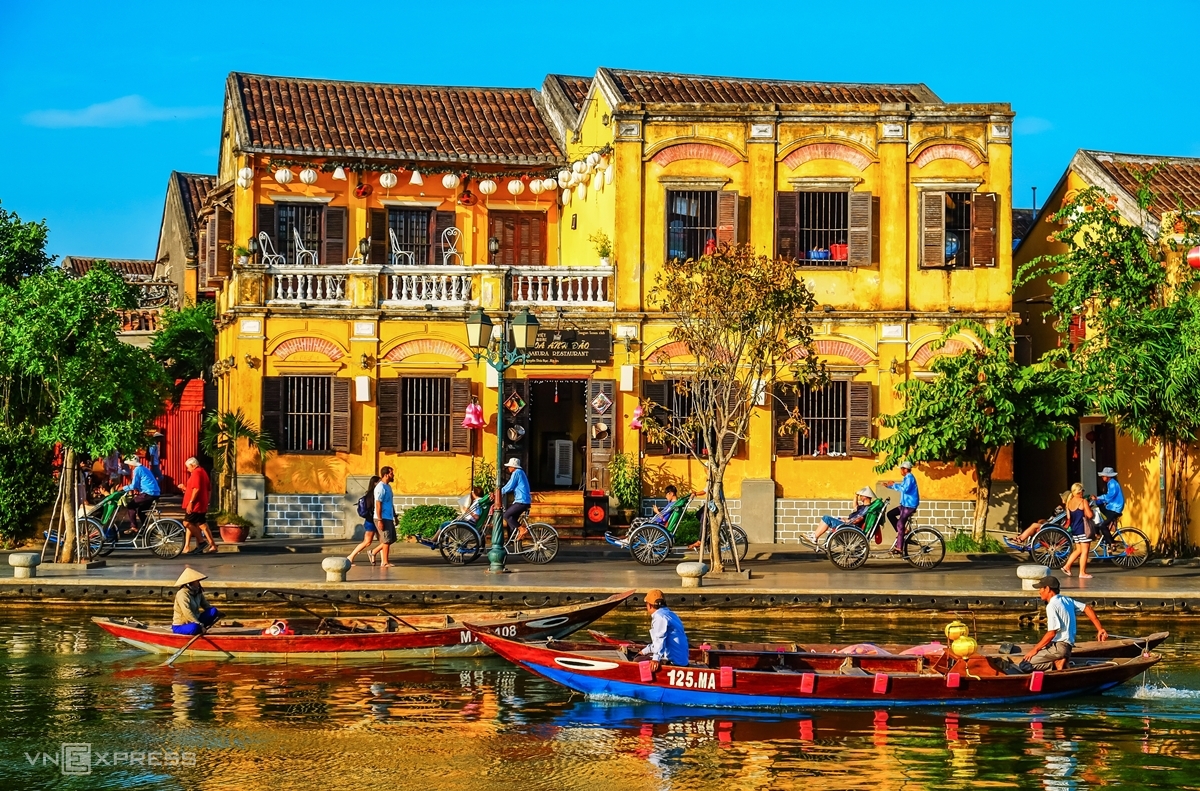 Toruists enjoy boat and cyclo tours along the Hoai River in Hoi An ancient town